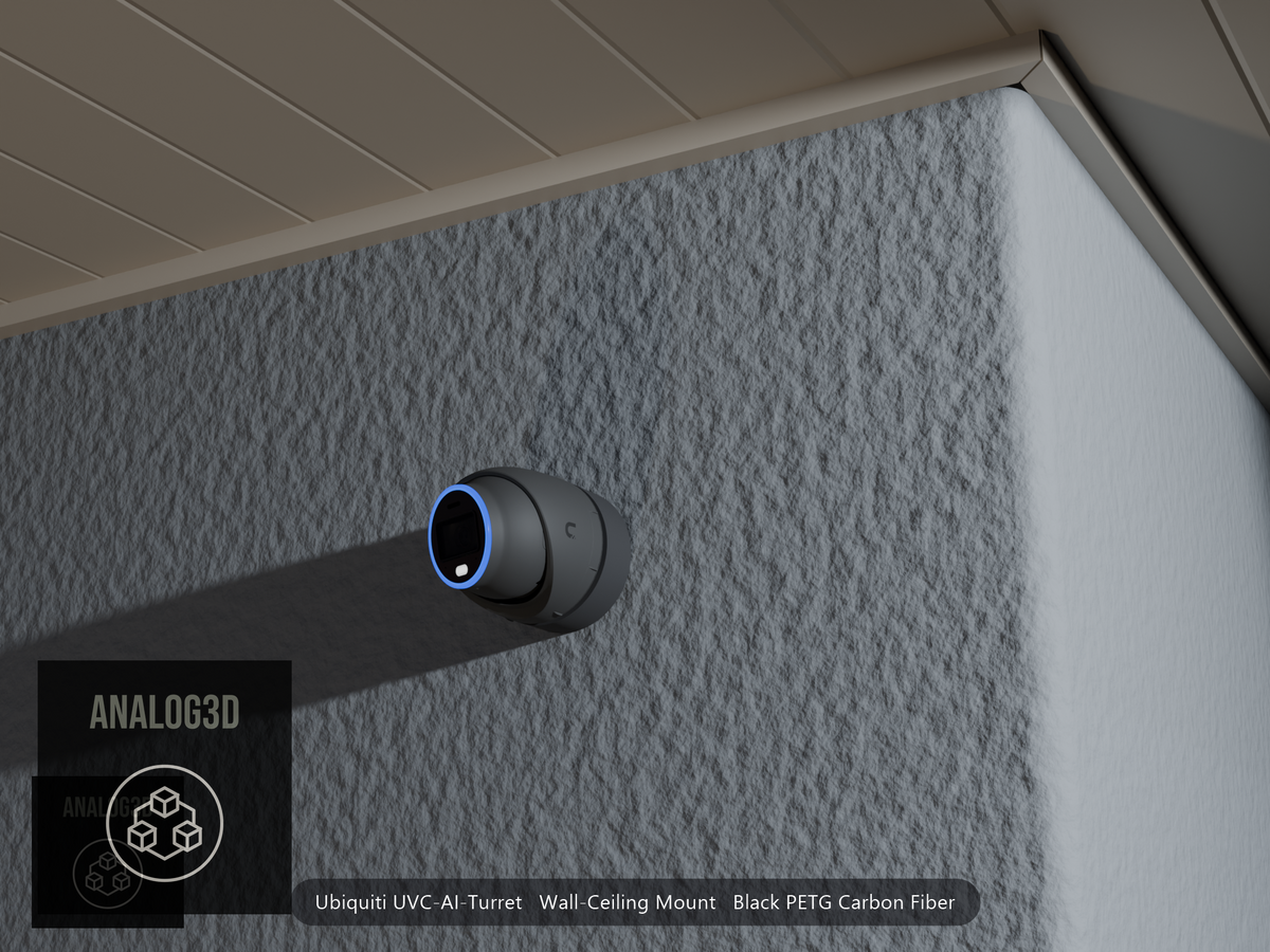 Ubiquiti UVC-AI-Turret wall mount in black PETG carbon fiber on a stucco wall at night
