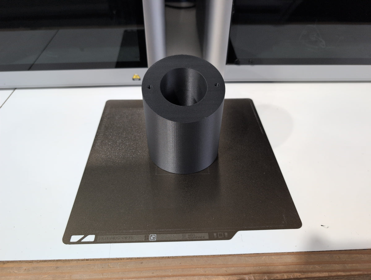 Unedited photo: UniFi angled soffit mount body, carbon fiber PETG, fresh off the print bed (same body across the UniFi soffit family)